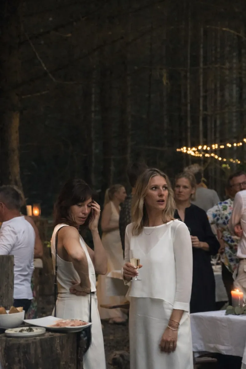 Bruid tussen haar gasten aan een tafel vol sharinggerechten in het bos